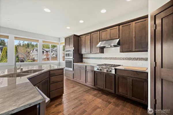 a kitchen with stainless steel appliances granite countertop wooden cabinets a sink and a stove