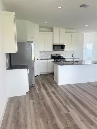 a kitchen with stainless steel appliances granite countertop a stove a sink and a refrigerator