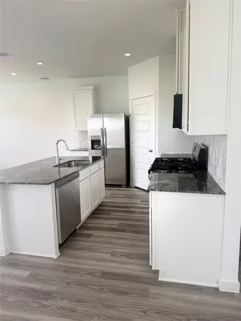 a kitchen with granite countertop a sink and a refrigerator