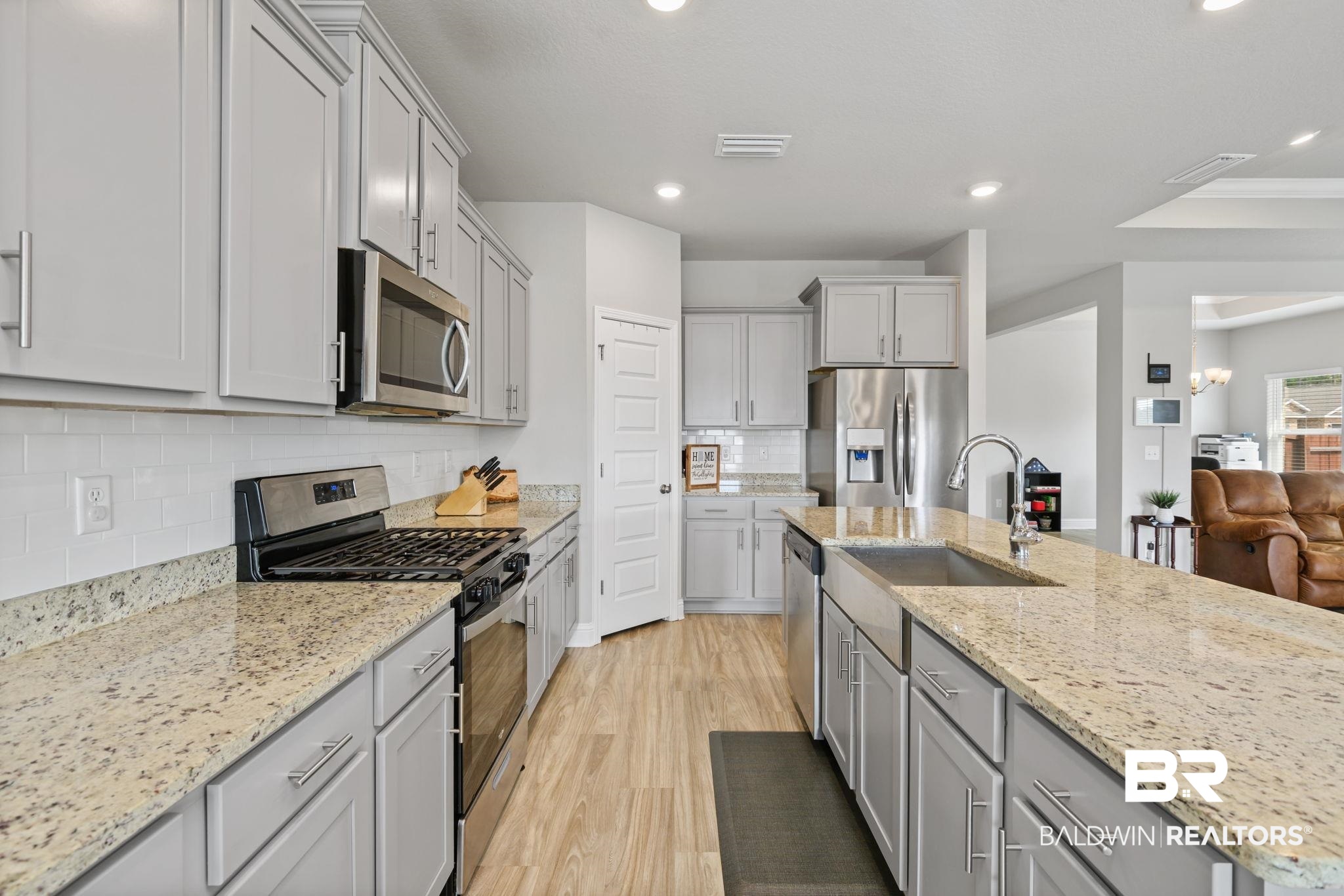 2183 Meadowview Loop Semmes, AL 36575 - Photo 36 of 58 Kitchen featuring stainless steel appliances, gray cabinetry, light wood finished floors, a kitchen island with sink, and decorative backsplash