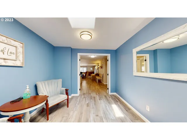 a living room with couches a table and a clock on the wall with wooden floor