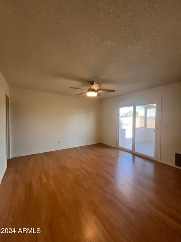 a view of empty room with wooden floor and fan