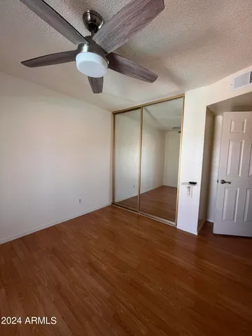 an empty room with wooden floor and chandelier fan