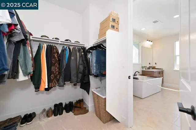 a walk in closet with clothes and shoes