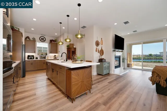 a large kitchen with stainless steel appliances kitchen island granite countertop a large stove a sink dishwasher and a fireplace with wooden floor