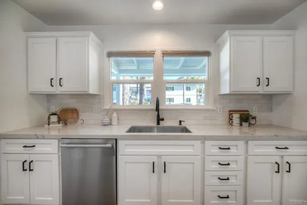 a kitchen with stainless steel appliances granite countertop white cabinets sink and window