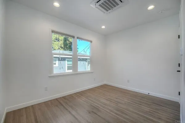 an empty room with wooden floor and windows