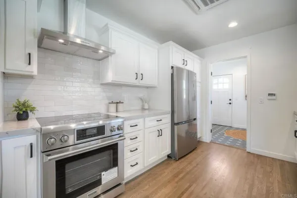 a kitchen with stainless steel appliances a stove a refrigerator and a hard wood floors