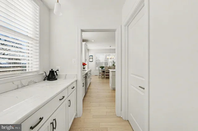 a kitchen with stainless steel appliances kitchen island granite countertop a dining table chairs and white cabinets