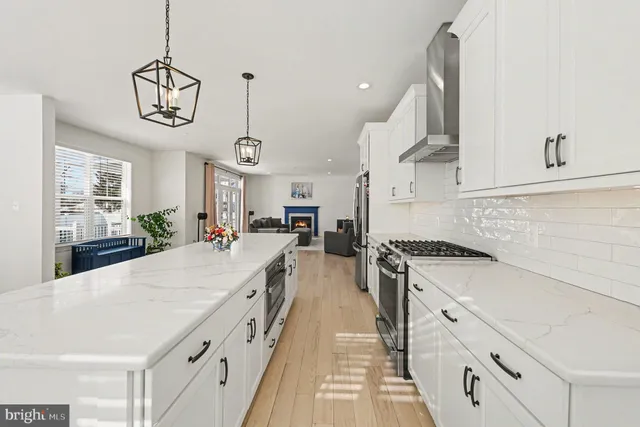 a kitchen with stainless steel appliances a refrigerator a stove top oven a dining table and chairs with wooden floor