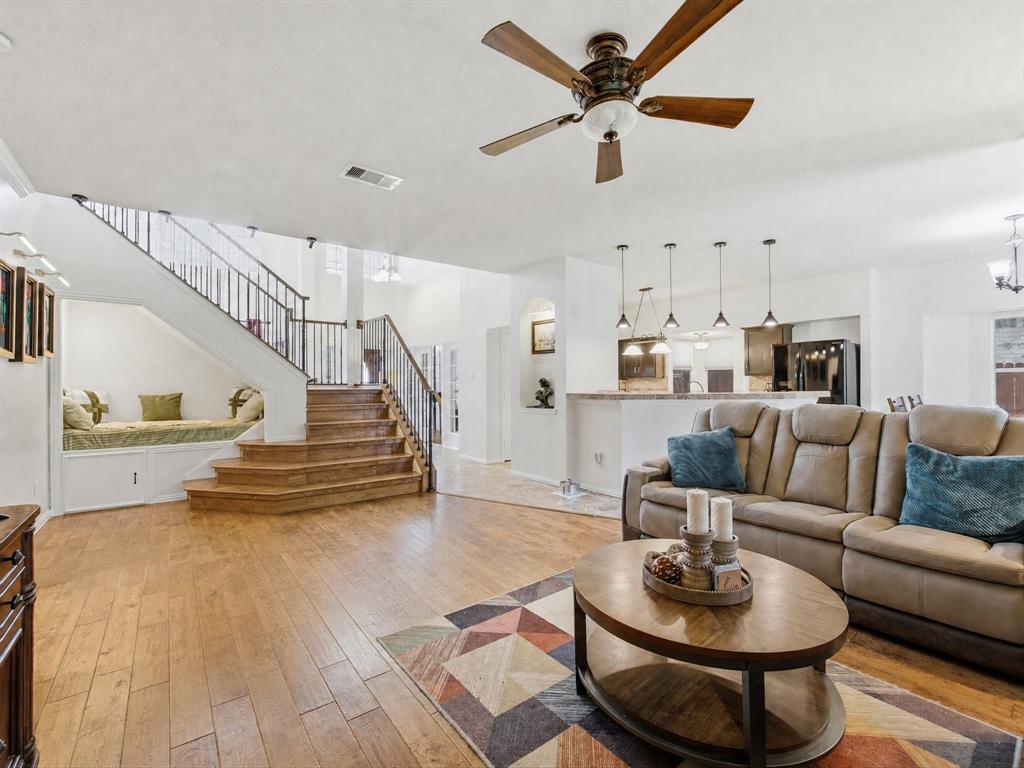 4008 Falcon Ridge Drive Haltom City, TX 76137 - Photo 15 of 40 Open-concept living space featuring wood-finish flooring, a contemporary ceiling fan, and a built-in window seat under the staircase