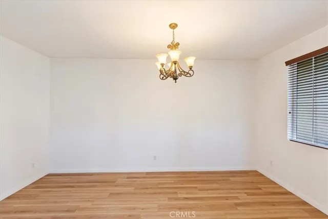 a view of a hallway with wooden floor and a chandelier