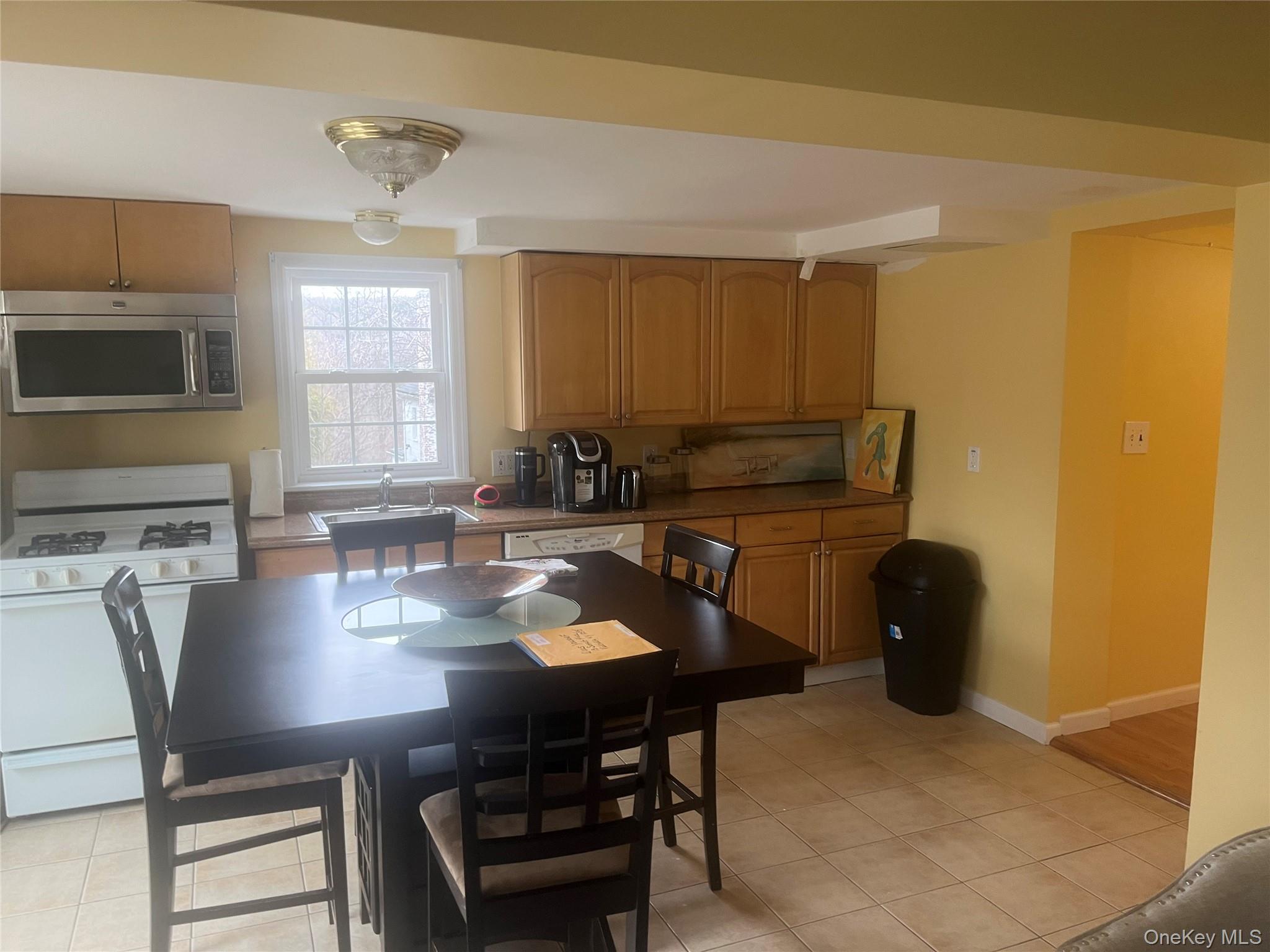 13 Summitt Place Valhalla, NY 10595 - Photo 4 of 10 a kitchen with a dining table chairs and a refrigerator