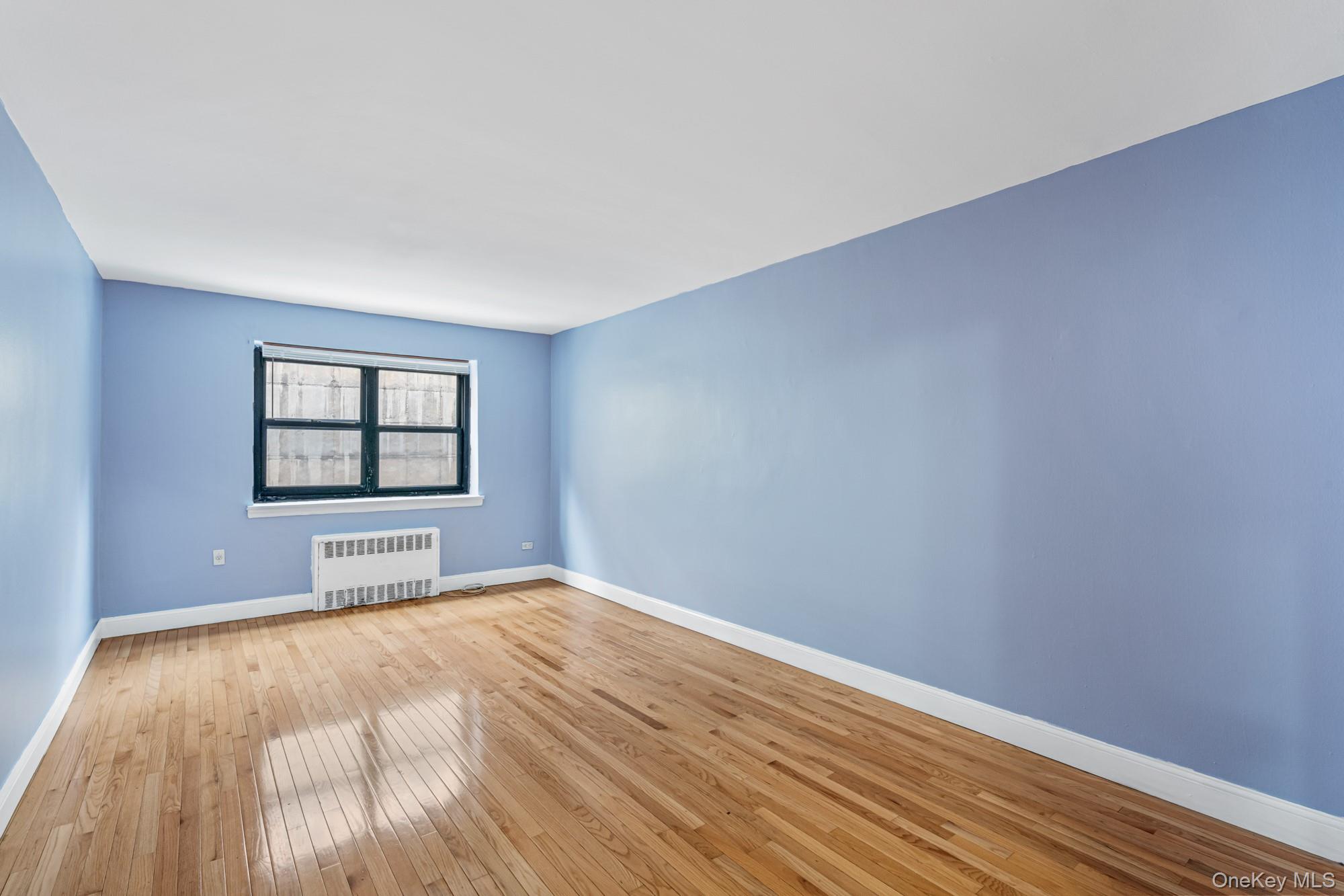 102-55 67th Road, Unit 2V Queens, NY 11375 - Photo 5 of 14 wooden floor in an empty room with a window