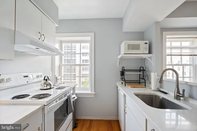 a kitchen with stainless steel appliances wooden floor and a window
