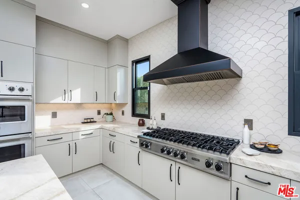 a kitchen with white cabinets and appliances