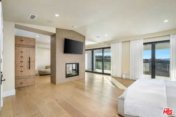 a spacious bedroom with a balcony and a fireplace