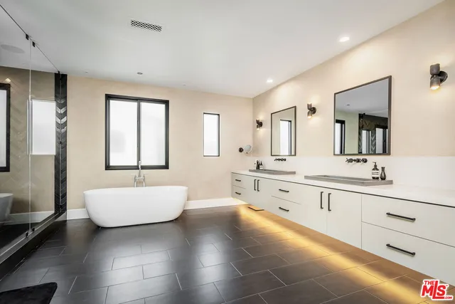 a large bathroom with a double vanity sink a mirror and a bathtub