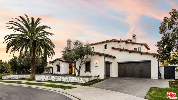 a front view of a house with a garden and palm trees