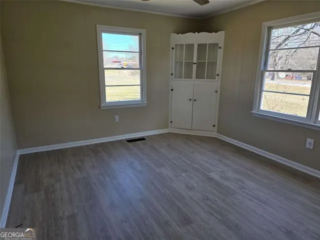 an empty room with wooden floor and windows