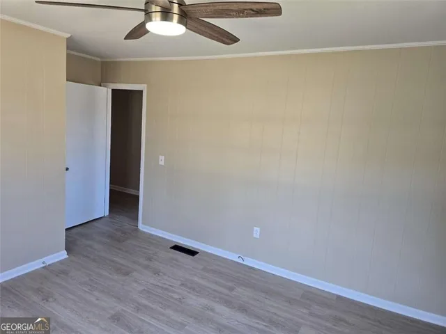 an empty room with wooden floor fan and a window