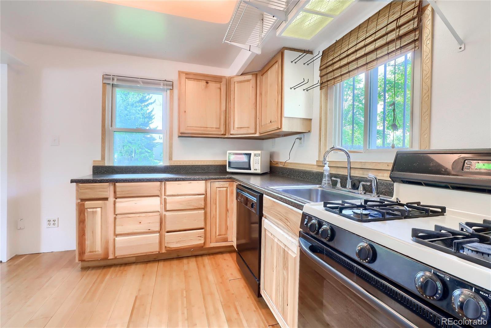 6201 East Tennessee Avenue Denver, CO 80224 - Photo 7 of 25 a kitchen with stainless steel appliances kitchen island wooden cabinets a stove a sink and a window