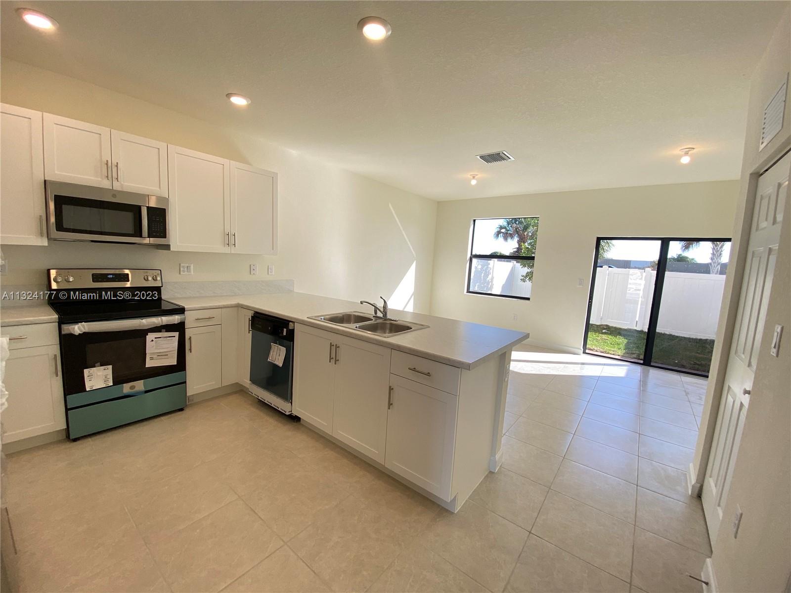 Hialeah Hialeah, FL 33018 - Photo 4 of 30 a large kitchen with stainless steel appliances granite countertop a stove a sink dishwasher and a microwave with wooden floor