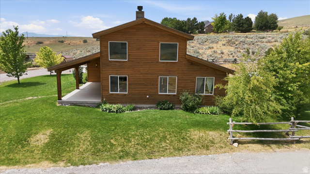 715 Ranch Loop Road Preston, ID 83263 - Photo 69 of 77 Wood-sided home featuring a covered porch, stone chimney, and a sloped lawn