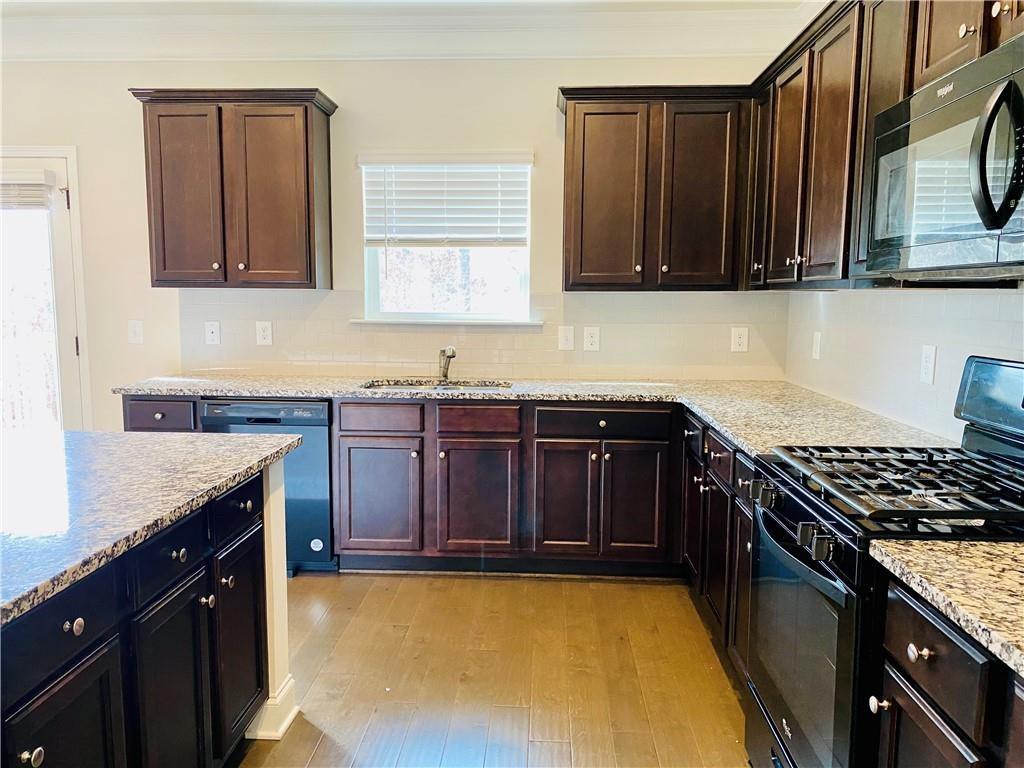 5101 Woodline View Circle Auburn, GA 30011 - Photo 5 of 26 a kitchen with stainless steel appliances granite countertop a stove a sink dishwasher and cabinets with wooden floor