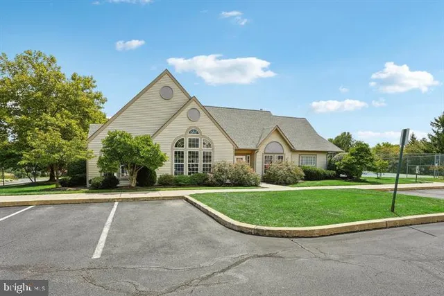 a view of a white house next to a yard with big trees