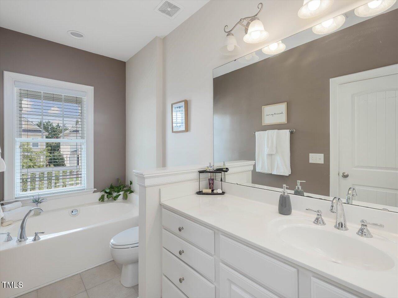 7712 ACC Boulevard Raleigh, NC 27617 - Photo 23 of 38 a bathroom with a double vanity sink a toilet and bathtub