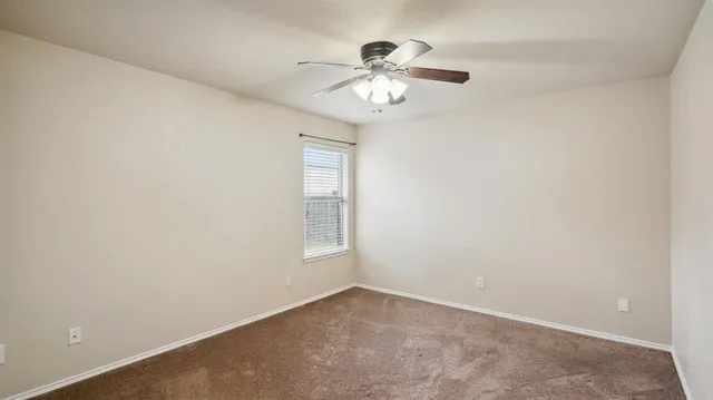 en empty room with windows and chandelier fan