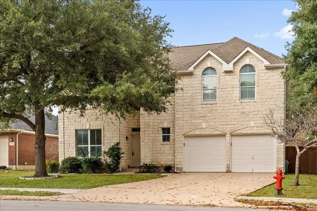 a view of a white house with large trees and plants