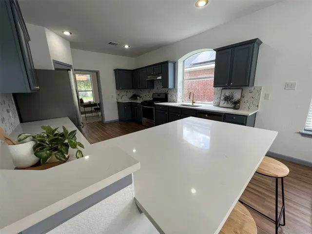 a large white kitchen with a sink potted plants and large window