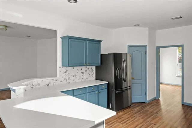 a kitchen with stainless steel appliances a refrigerator sink and wooden floor