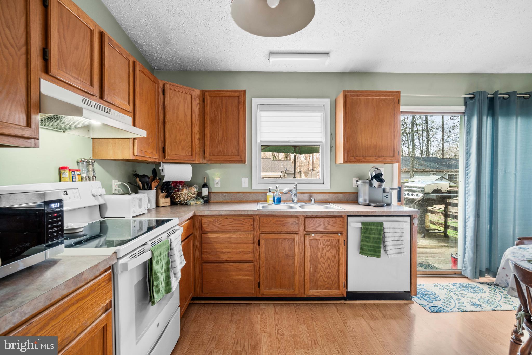 11543 San Rafael Road Lusby, MD 20657 - Photo 7 of 20 a kitchen with stainless steel appliances granite countertop wooden cabinets a sink a stove a window and island
