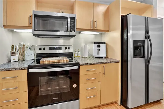 a kitchen with stainless steel appliances granite countertop a stove microwave and refrigerator