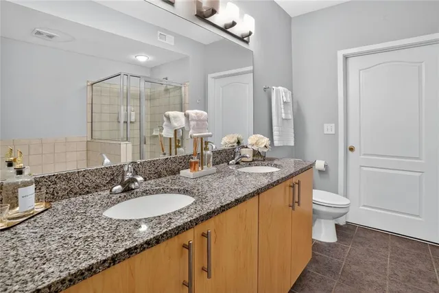 a bathroom with a granite countertop sink a toilet a mirror and shower