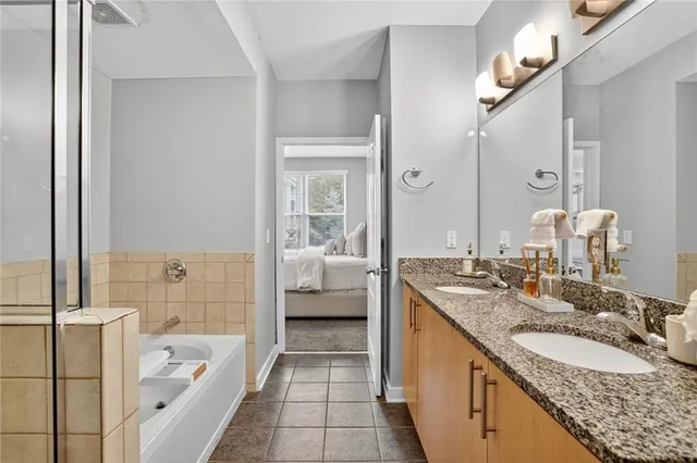 a en suite bathroom with a granite countertop double vanity sink a mirror and a bathtub