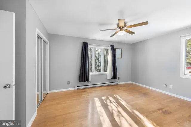 a view of an empty room with window and ceiling fan