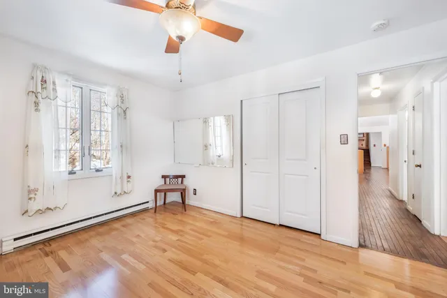 a view of empty room with wooden floor and fan