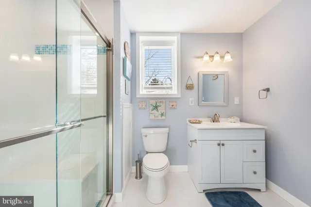 a bathroom with a toilet a sink a mirror and a window