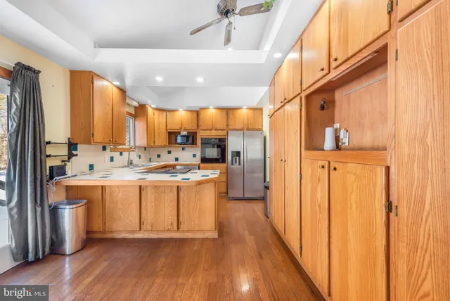 a large kitchen with stainless steel appliances a large counter top a stove a chimney a sink and cabinets