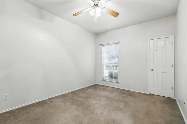 an empty room with chandelier fan and windows