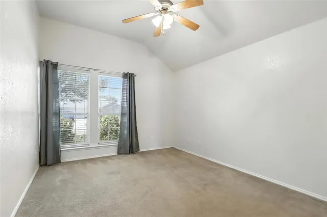 an empty room with windows and ceiling fan