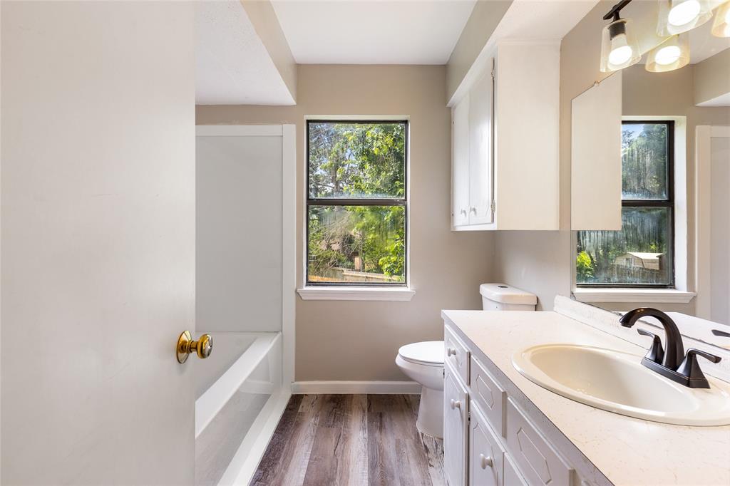 2820 Bois D'Arc Street Commerce, TX 75428 - Photo 23 of 40 a bathroom with a sink a bathtub and a window