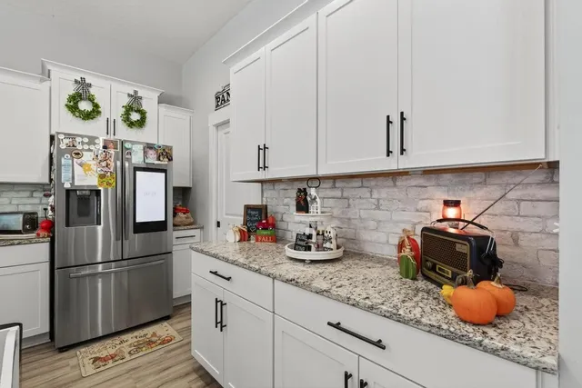 a view of a kitchen with kitchen island a white counter top space a sink and a refrigerator