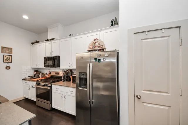 a kitchen with stainless steel appliances a refrigerator sink and white cabinets