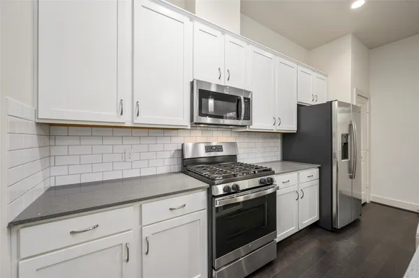 a kitchen with granite countertop white cabinets and stainless steel appliances
