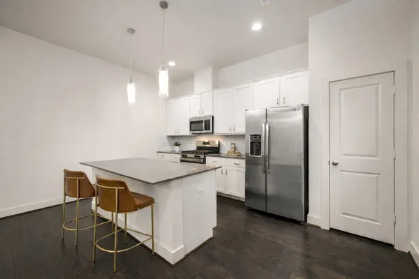 a kitchen with stainless steel appliances granite countertop a refrigerator a stove a sink dishwasher and a refrigerator with wooden floor